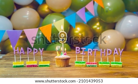 Happy birthday for 9 year old baby greeting card, festive cupcake with burning candles and birthday decorations on a blue background