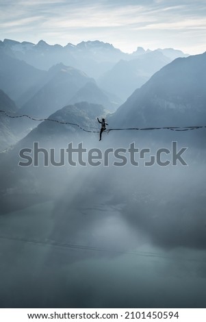 brave woman on slackline in mountains over lake Royalty-Free Stock Photo #2101450594