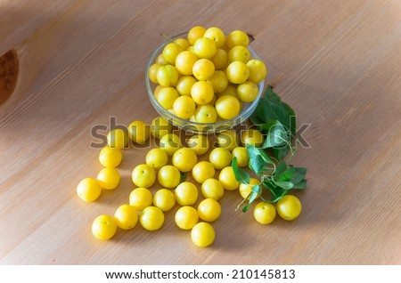 pile of yellow mirabelle plums on wooden table - stock photo
