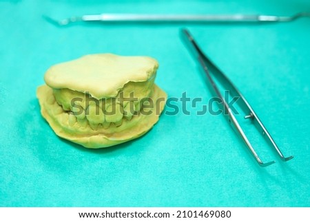 denture plaster mold with dentist utensils around on blue paper