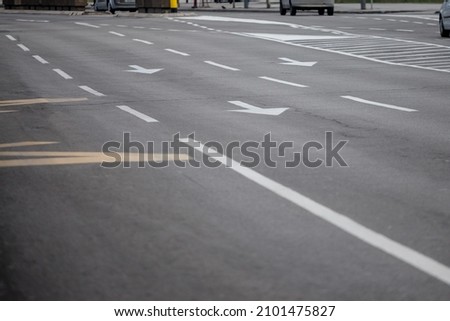 Selective blur on lane markings with painted directional arrows on thru lanes on asphalt, on a city urban road used for heavy traffic, in Europe, abiding by european standards.  Royalty-Free Stock Photo #2101475827