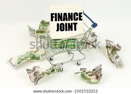 Business and economy concept. Crumpled dollars lie on a white surface, there is a cart inside a sign with the inscription - FINANCE JOINT
