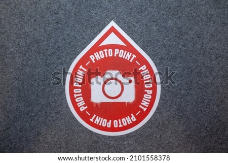 on a grey floor is a red sticker with a white camera and the inscription: Photo point. Note in a museum that you can take a good photo there. 