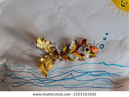 Naive beautiful three dimensional art work of a kid displaying a fish made out of autumn leafs