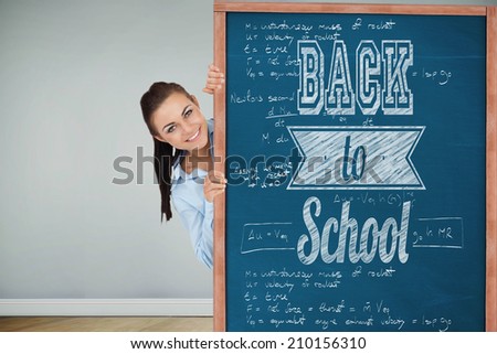 Smiling businesswoman looking around the corner against blackboardon wooden board