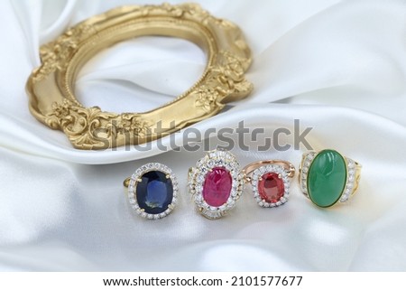 High jewelry banner with color natural gemstone and diamonds on gold ring setting. White satin with tray background for jewelry shop