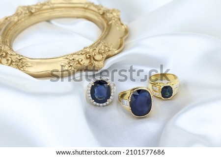 High jewelry banner with color natural gemstone as Blue sapphire and diamonds on gold ring setting. White satin with tray background for jewelry shop