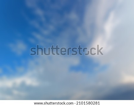 Defocused abstract background of blue sky with white and gray clouds forming bird's wings