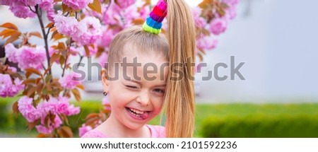 Banner with spring kids portrait. Spring funny portraits gorgeous little girl on cherry blossom background. Winking on the camera.