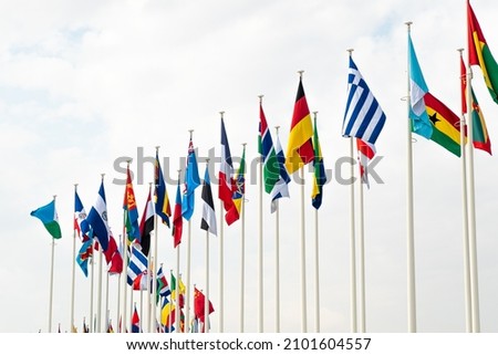 Flags of different nations waving together. Blue sky background. Royalty-Free Stock Photo #2101604557