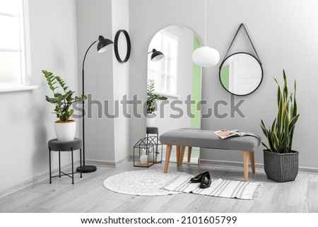 Interior of light hallway with mirrors, ottoman and houseplants Royalty-Free Stock Photo #2101605799
