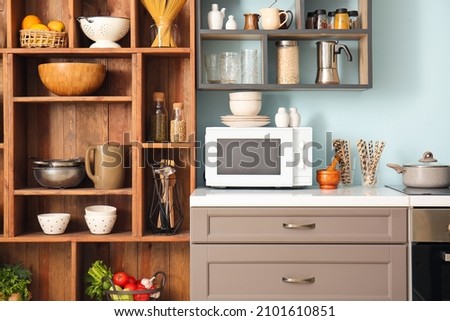 Interior of stylish kitchen with counter, microwave oven and shelves