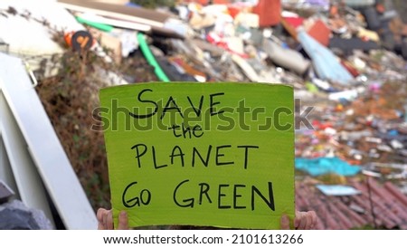 sign with Save the Planet go green, environmental protest against climate change, global warming and air pollution in an illegal polluting waste dump