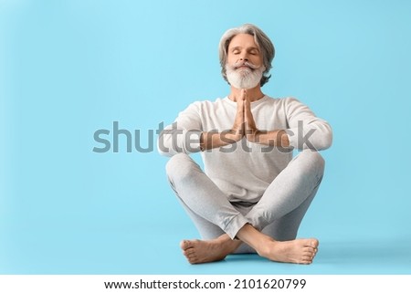 Mature man practicing yoga on color background