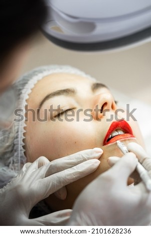 Professional permanent makeup artist and her client during lip blushing procedure Royalty-Free Stock Photo #2101628236