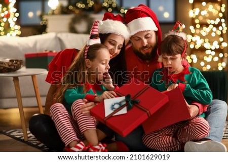 Happy family with kids opening present at home on Christmas eve