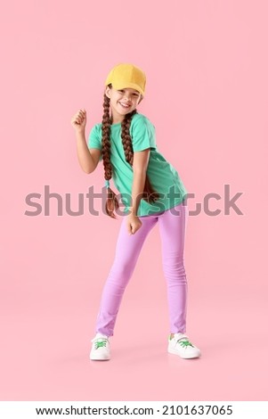 Cute little girl in cap dancing on pink background Royalty-Free Stock Photo #2101637065