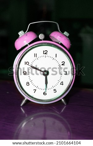 Photo of an old pink clock that stands on the table