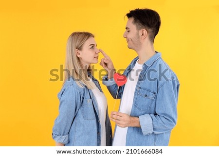 Cute couple with heart on yellow background