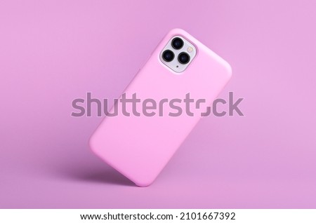 iPhone 11 and 12 Pro max in pink silicone case falls down back view, phone case mockup isolated on pink background Royalty-Free Stock Photo #2101667392