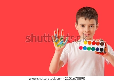 Little boy with paints on color background