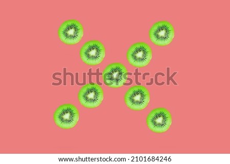 Letter X made with kiwi slices, top view kiwi slices isolated on pink background.