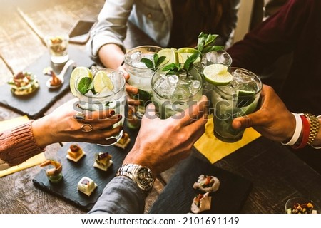 Happy friends group cheering mojito drinks at cocktail bar restaurant - Young people having fun drinking cocktails on happy hour at pub - Party time and youth concept	
 Royalty-Free Stock Photo #2101691149