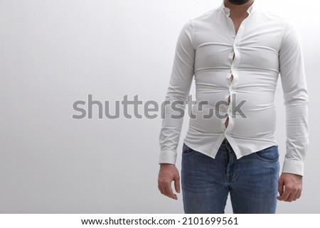 Man wearing tight shirt on white background, closeup. Overweight problem Royalty-Free Stock Photo #2101699561