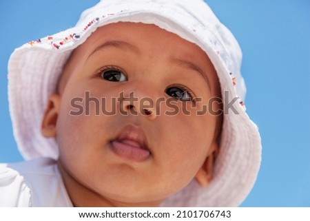 Close-up face of 6 month old baby girl wearing white floral cotton hat