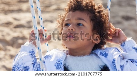 3 year old leaning back while swinging on a playground swing