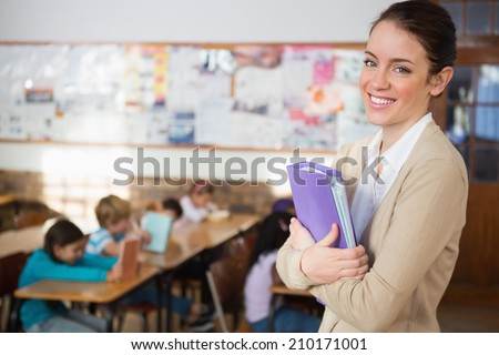 Pretty teacher smiling at camera at back of classroom at the elementary school Royalty-Free Stock Photo #210171001