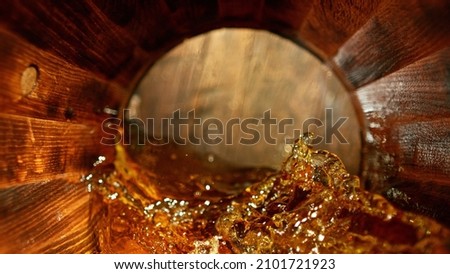 Freeze motion of splashing whisky in wooden barrel. Concept of pouring whisky, rum or cognac inside a keg. Alcoholic beverage background. Royalty-Free Stock Photo #2101721923
