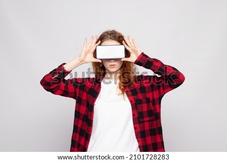 girl in a plaid shirt on a light background with a smartphone