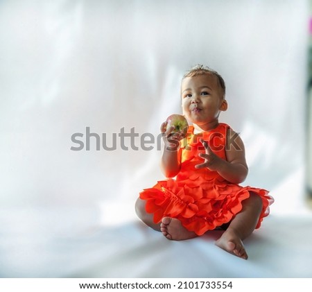 10 month old baby holding an apple In Studio