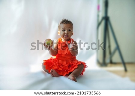 10 month old baby holding an apple In Studio
