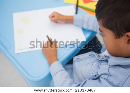 Cute little boy drawing at desk at the nursery school