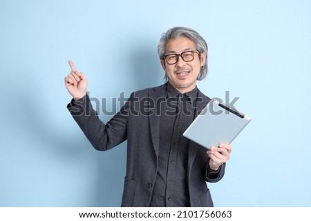 The senior Asian businessman standing on the blue background.