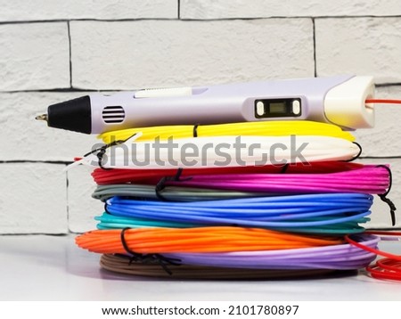 3 d pen with colored plastic on a gray brick background