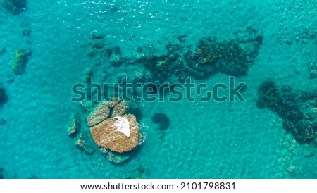 Aerial view of calm turquoise sea water and underwater rocks from drone. Waves on stones in the middle of the sea. Royalty-Free Stock Photo #2101798831