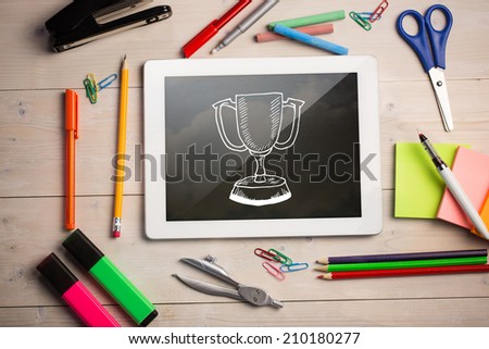 Composite image of digital tablet on students desk showing winners cup doodle