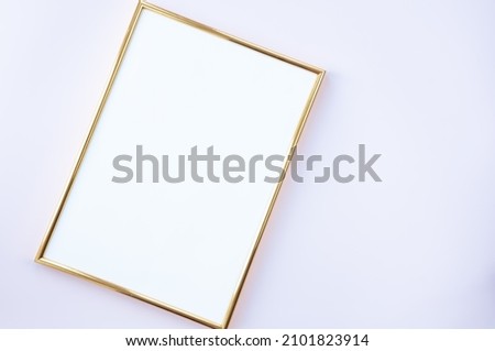 Empty frame on gentle pink background. A golden photo fra,e lying on background with place for your text. Mock up.