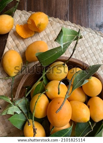 Plum mango, or scientifically known as Bouea oppositifolia, a popular tropical fruit in Southeast Asia, isolated on dark wooden table with some shadow and selective focus.
