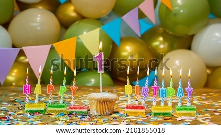 Cupcake with a candle one year old, Greeting colorful card happy birthday to the child 1 year old, birthday cupcake with candles and birthday decorations on the background. Copy space