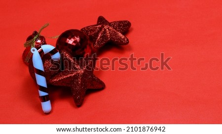 A closeup shot of star-shaped, candy-shaped, and ball-shaped Christmas tree toys on a red background