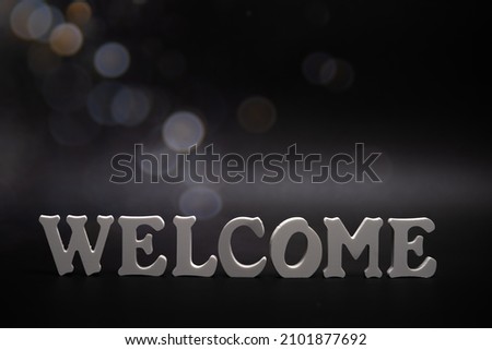 WELCOME word made with white letters on dark background.