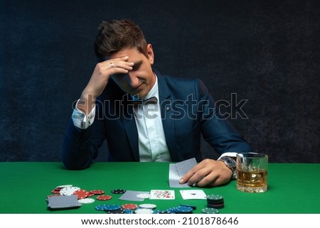 Upset poker player in casino with bad poker cards. Royalty-Free Stock Photo #2101878646
