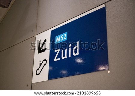 A Sign for escalator and direction south on the north-south line subway in Amsterdam, Netherlands