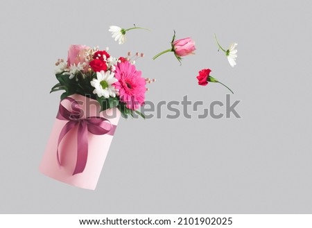 Pink gift box with various flowers on grey background. Flying flowers from the box. Valentines day aesthetic nature concept. 8 March card idea. Royalty-Free Stock Photo #2101902025
