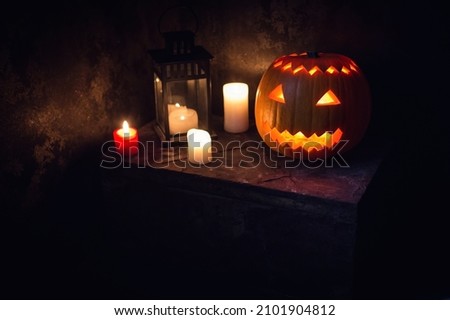 Halloween pumpkin head jack lantern with burning candles over dark background. 
