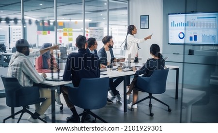 Diverse Modern Office: Black Businesswoman Leads Business Meeting with Managers, Talks, uses Presentation TV with Statistics, Graphs, Big Data. Digital Entrepreneurs Work on eCommerce Project Royalty-Free Stock Photo #2101929301